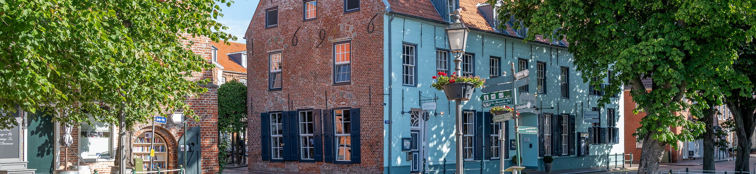 Historische Häuser und Straßen in Greetsiel mit Bäumen im Vordergrund